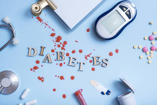 Word DIABETES with insulin syringe,lancet,test, glucose meter on blue background. - Fotó, kép
