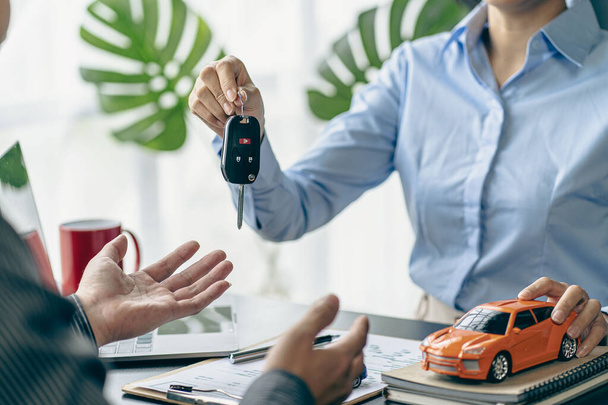 of the representative Hold the car keys to the new owner after signing the leasing contract in the car sales contract document. - Foto, Imagen
