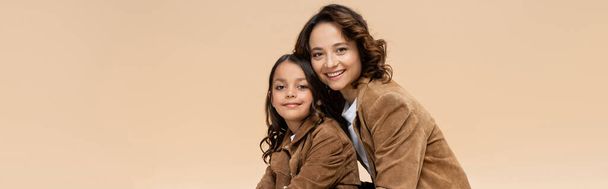 cheerful woman in autumn jacket looking at camera near trendy daughter isolated on beige, banner - Fotoğraf, Görsel