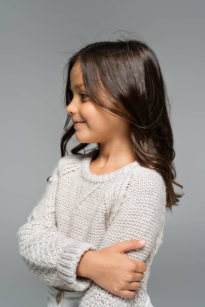 pleased brunette girl in warm knitted sweater looking away isolated on grey - Фото, изображение
