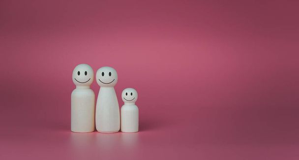 Happy house concept. Wooden dolls stand lined up against a pink background. Indicates happiness and love in the house. - Photo, Image
