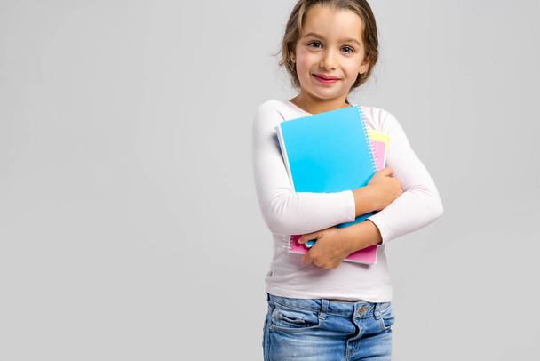 Smiling little student girl holding notebooks - Foto, Imagen