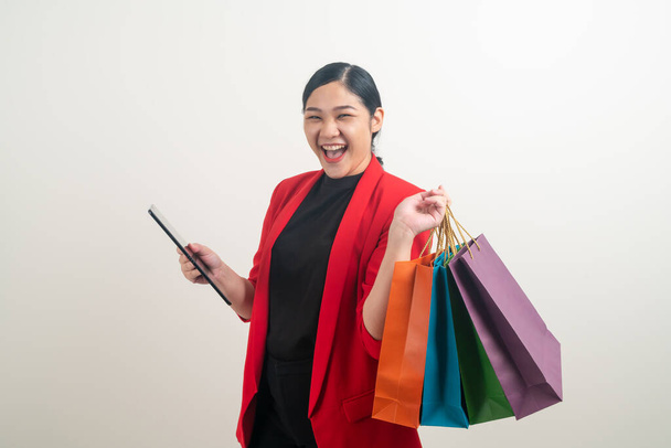 Asian woman holding shopping bag and tablet on hand with white background - Фото, изображение