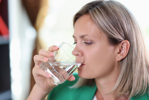 Porträt einer durstigen Frau, die Wasser aus durchsichtigem Glas trinkt. Wasserhaushalt und Gesundheitskonzept - Foto, Bild
