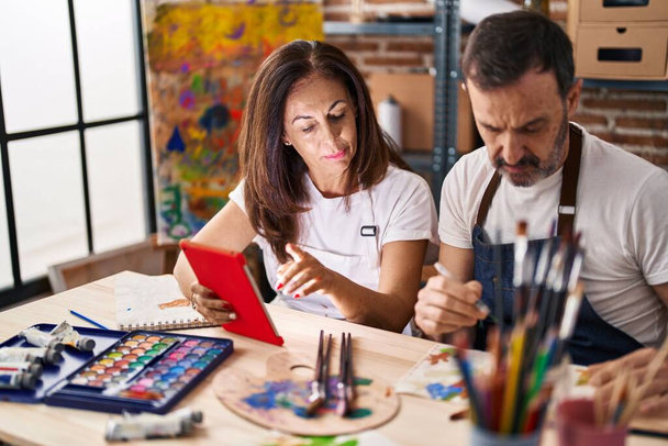 Orta yaşlı erkek ve kadın sanatçılar sanat stüdyosunda dokunmatik kağıt kullanarak defter çiziyorlar. - Fotoğraf, Görsel