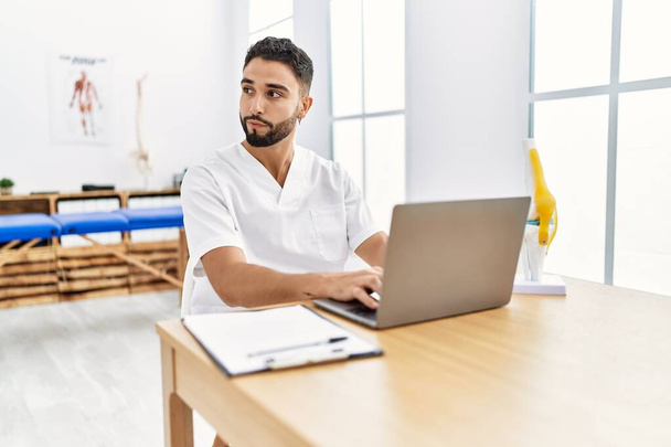 Young arab man wearing physiotherapist uniform using laptop at clinic - Photo, Image