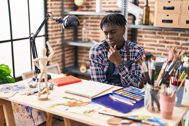 Artista afroamericano uomo guardando notebook con espressione dubbio a studio d'arte - Foto, immagini
