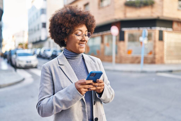 Afrikai amerikai nő végrehajtó mosolygós magabiztos segítségével smartphone az utcán - Fotó, kép