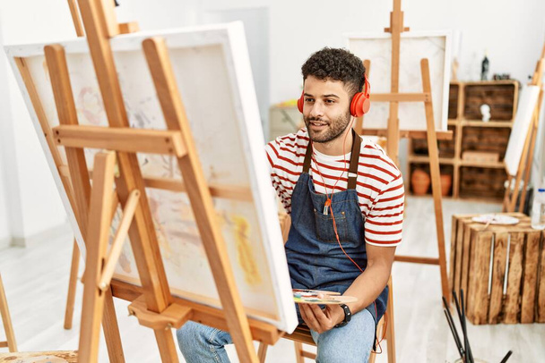 Jeune artiste arabe homme écoutant de la musique dessin au studio d'art. - Photo, image