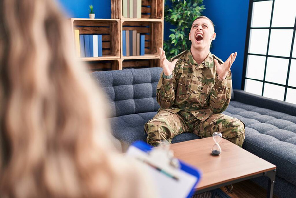 Young man doing therapy after war crazy and mad shouting and yelling with aggressive expression and arms raised. frustration concept.  - Foto, imagen