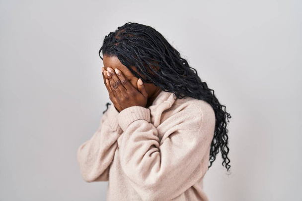 Donna africana in piedi su sfondo bianco con triste espressione che copre il viso con le mani mentre piange. concetto di depressione.  - Foto, immagini