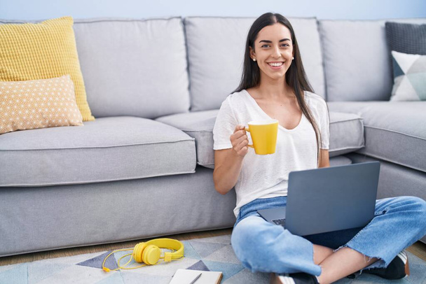 Young hispanic woman using laptop drinking coffee at home - Foto, immagini