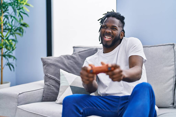 African american woman playing video game sitting on sofa at home - Photo, Image