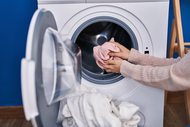 Молода жінка миє одяг у пральні
 - Фото, зображення