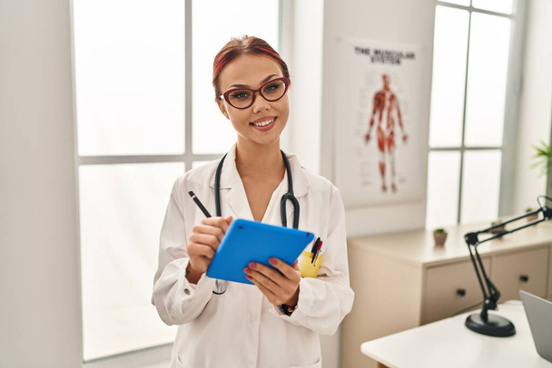 Giovane medico donna caucasica utilizzando touchpad in piedi presso la clinica - Foto, immagini
