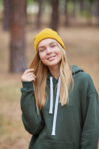 Closeup portrait of gorgeous young blonde Caucasian woman in knitted beanie in autumn in park. Young woman head shot, natural light, retouched, vibrant colors. - Zdjęcie, obraz