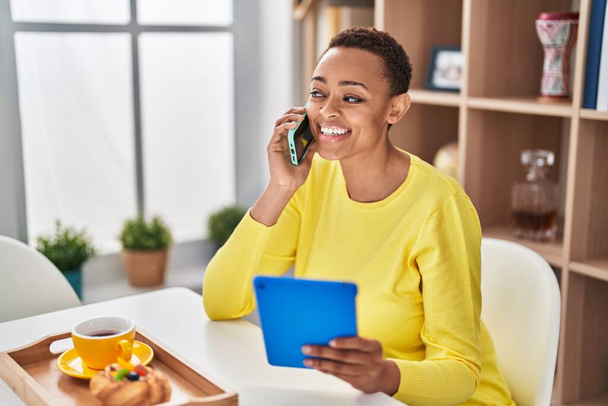 Afričanky americká žena mluví na smartphone pomocí touchpad doma - Fotografie, Obrázek