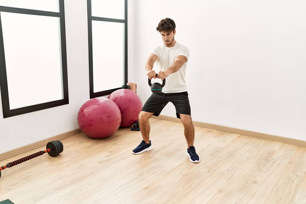 Young hispanic man training with kettlebell at sport center - Foto, immagini