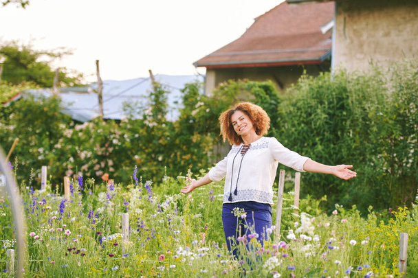 Venkovní portrét krásné 50 letá žena těší pěkný den v květinovém parku nebo zahradě, šťastný a zdravý životní styl - Fotografie, Obrázek