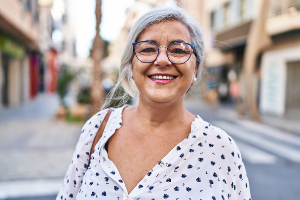 Женщина средних лет уверенно улыбается стоя на улице - Фото, изображение