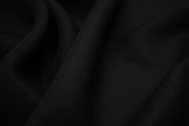Texture of dark black fabric closeup. Low key photo. Plexus threads. Clothing industry. Abstract background. Black textile waves. Black cloth background - Фото, изображение