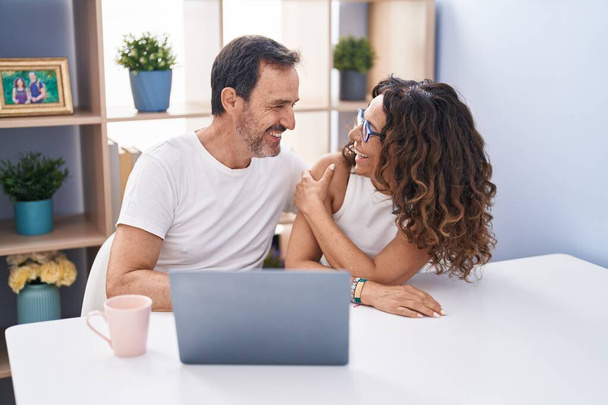 Kadın ve erkek evde dizüstü bilgisayar kullanarak gülümsüyor. - Fotoğraf, Görsel