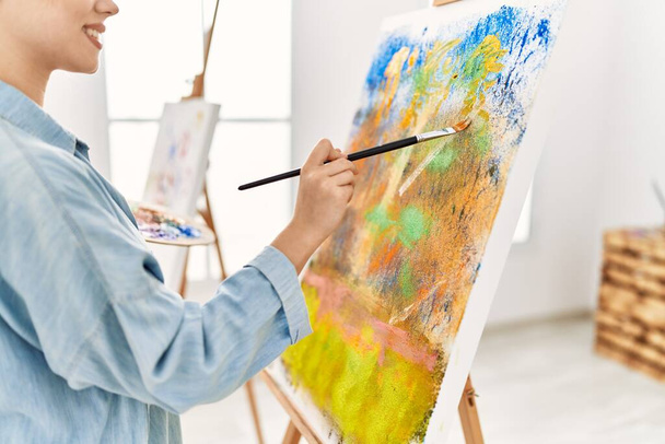 Молода біла жінка художник посміхається впевнено малює в художній студії
 - Фото, зображення