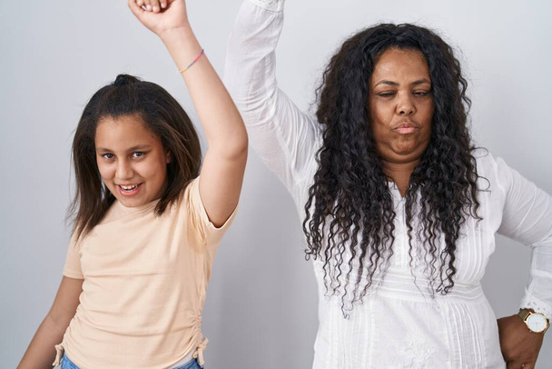Anne ve küçük kızı beyaz arka planda dans ediyor mutlu ve neşeli, hareketli ve kendinden emin müzik dinliyor.  - Fotoğraf, Görsel