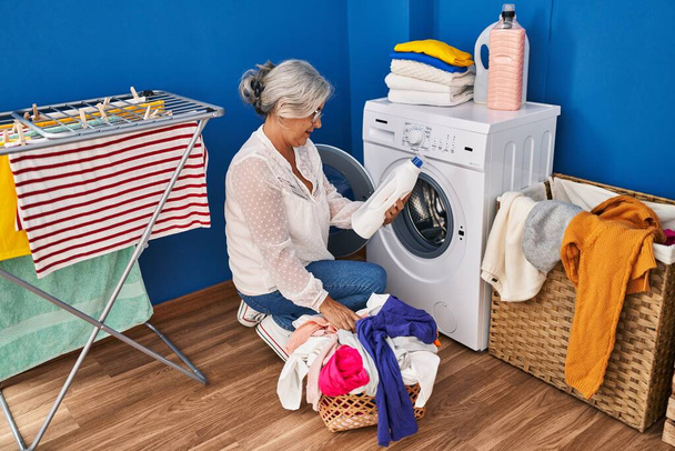 Middle age woman washing clothes at laundry room - Photo, Image