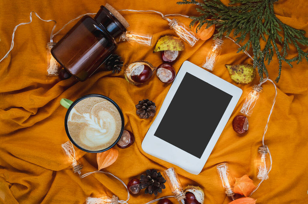 Jesienny dom przytulny kompozycja z pomarańczowym kratę, świecące słoiki, filiżanka kawy, kasztany i e-book z miejsca do kopiowania. Jesienny szablon sezonu dla kobiecych blogów social media. - Zdjęcie, obraz