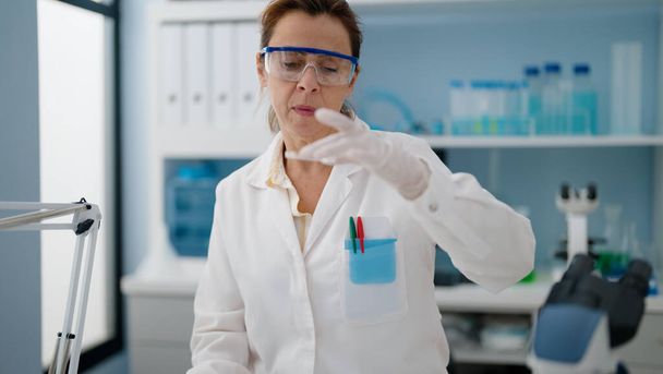 Laboratuvarda çalışan orta yaşlı İspanyol kadın bilim adamı üniforması giyiyor. - Fotoğraf, Görsel