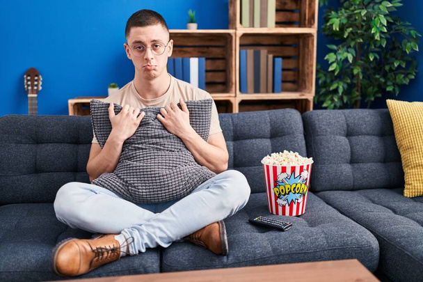 Jongeman die popcorn eet depressief en zich zorgen maakt om verdriet, huilend boos en bang. trieste uitdrukking.  - Foto, afbeelding