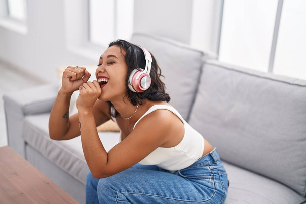 Junge schöne hispanische Frau hört Musik, die zu Hause Lieder singt - Foto, Bild