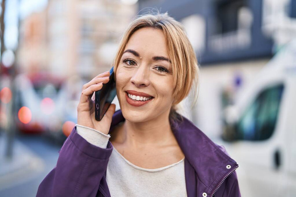 Jeune femme souriant confiant parler sur le smartphone à la rue - Photo, image