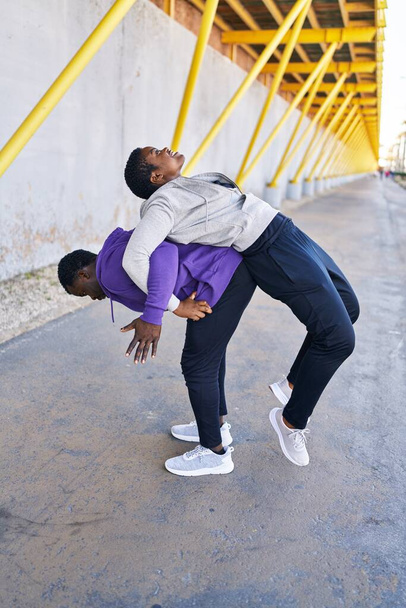 Man and woman couple wearing sportswear stretching at street - Photo, Image