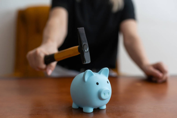 Person smashing piggy bank with hammer - 写真・画像