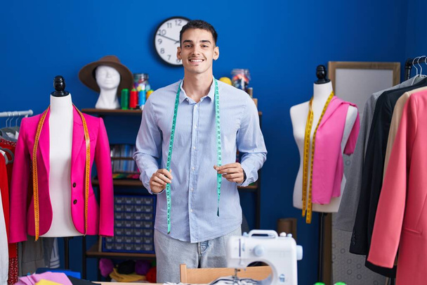 Young hispanic man tailor smiling confident standing at sewing studio - Foto, imagen
