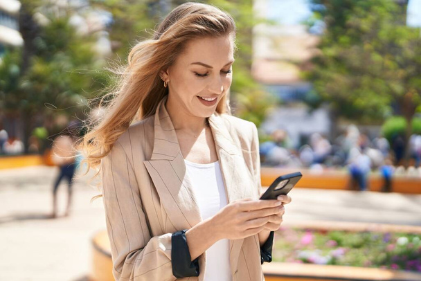 Young blonde woman smiling confident using smartphone at park - Photo, Image