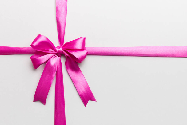 Top view of purple ribbon rolled and pink bow isolated on colored background. Flat lay with copy space. - Photo, Image