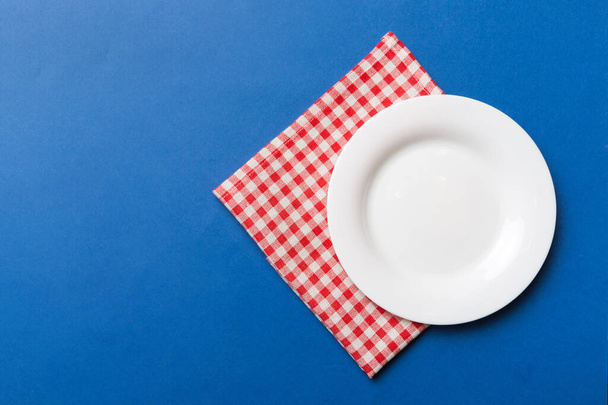 Top view on colored background empty round white plate on tablecloth for food. Empty dish on napkin with space for your design. - Photo, Image
