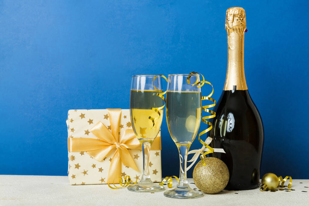 Champagne bottle with confetti, glasses and christmas decor on colored holiday background. Flat lay New Year decorations. - Fotografie, Obrázek