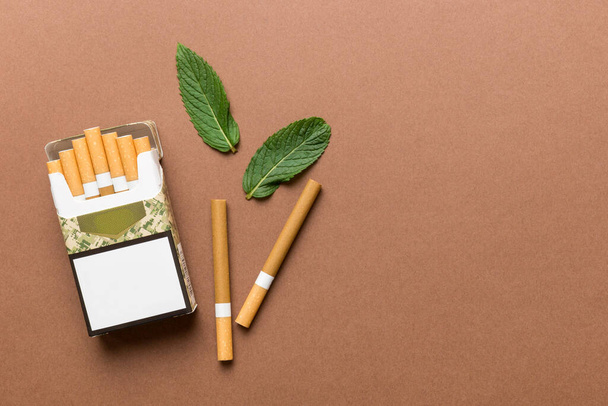 Pakkaus mentoli savukkeita ja tuoretta minttua värillinen pöytä, mentoli savukkeiden ylhäältä näkymä tasainen lay. - Valokuva, kuva