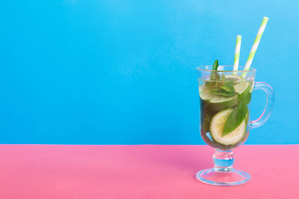 Мохито летом освежающий коктейль со льдом и мятой. коктейль мохито с лаймом, лимоном и мятой в высоком стакане с палкой. - Фото, изображение