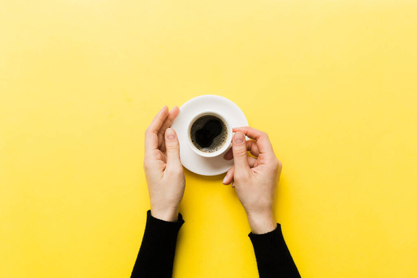 Minimalistinen tyyli nainen käsi pitämällä kuppi kahvia värillinen tausta. Tasainen, ylhäältä näkyvä espressokuppi. Tyhjä paikka tekstille, kopioi tilaa. Kahviriippuvuus. Top view, tasainen lay. - Valokuva, kuva