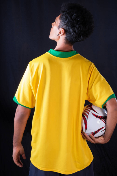 Brazilský fotbalový černošky hráč drží míč a slaví, izolované na černém pozadí. - Fotografie, Obrázek