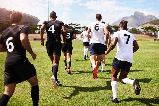 Die Gewinner stehen fest. eine Gruppe junger Rugbyspieler, die während eines Spiels auf das Spielfeld rennen - Foto, Bild