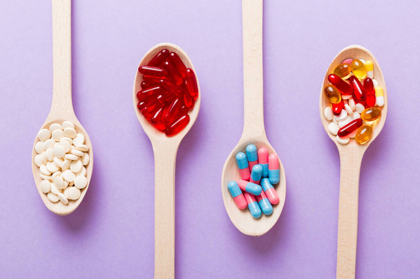 Vitamiinikapselit lusikassa värillisellä taustalla. Pillerit toimivat terveellisenä ateriana. Punainen pehmeä geeli vitamiinilisä kapselit lusikalla. - Valokuva, kuva