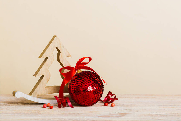 Рождественский бал с декоративной деревянной елкой на цветном фоне. украшение безделушки с бантом ленты с копировальным пространством. - Фото, изображение