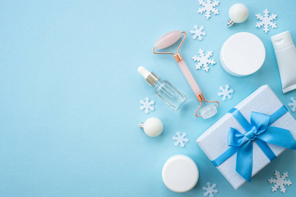 Χειμερινό καλλυντικό με χιονονιφάδες και διακόσμηση διακοπών. Χριστουγεννιάτικη πώληση και δώρο έννοια. Επίπεδη lay εικόνα με αντίγραφο χώρου στο μπλε. - Φωτογραφία, εικόνα