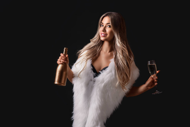 Beautiful gorgeous young woman in fur white cape holding champagne in hands stand while smiling celebrating something.  - Фото, изображение
